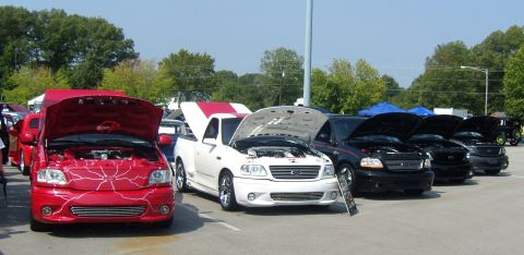 2007 Ford Mustang - Several pickup trucks, including a red one with custom graphics and a white one with a red stripe, are displayed with their hoods open.