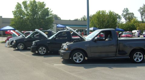 2007 Ford Mustang - Several Ford F-150 Lightning trucks are lined up with hoods open at an outdoor event.