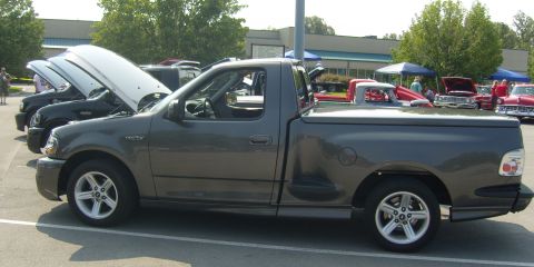 2007 Ford Mustang - A gray 2007 Ford F-150 SVT Lightning pickup truck is parked at an outdoor event with its hood up.