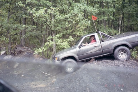 1979 Ford Bronco II - A gray pickup truck navigates a challenging off-road terrain, kicking up dust as it goes.