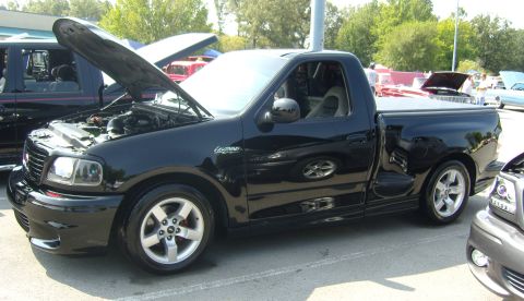 2007 Ford Mustang - Black 2001 Ford F-150 SVT Lightning pickup truck shown with its hood open at an outdoor event.