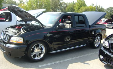 2007 Ford Mustang - A black pickup truck is parked with its hood and bed cover open, showing off its custom features.