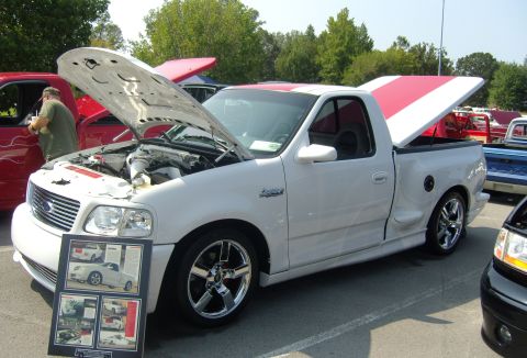 2007 Ford Mustang - A white pickup truck with a red and white striped tonneau cover is displayed with its hood open.