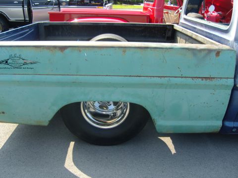 2007 Ford Mustang - A close-up side view of a vintage pickup truck bed with a spare tire visible inside.
