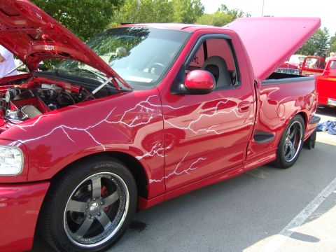 2007 Ford Mustang - This red pickup truck features custom lightning bolt graphics and has its hood and bed cover open.