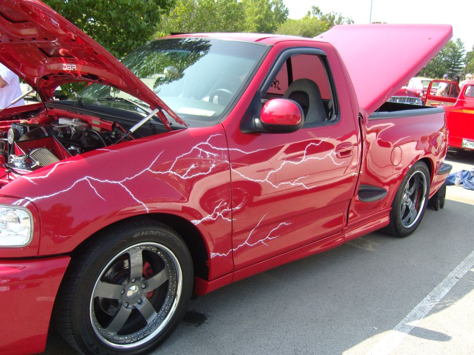 Red pickup truck with lightning bolt graphics, hood and bed cover open
