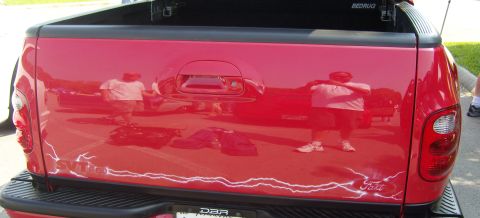 2007 Ford Mustang - Rear view of a red Ford F-150 SVT Lightning pickup truck, showing tailgate graphics and reflections.