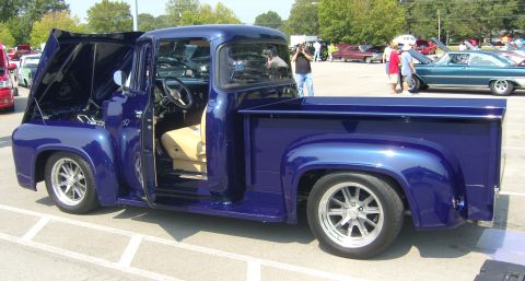 2007 Ford Mustang - A custom blue 1956 Ford F-Series pickup truck is displayed with its hood and door open at an outdoor car show.