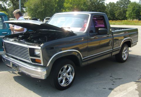 2007 Ford Mustang - This dark gray pickup truck features a prominent chrome grille and aftermarket wheels, with its hood open revealing the engine.