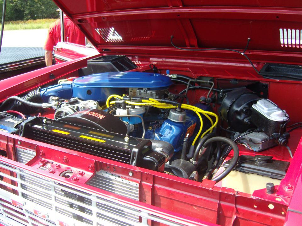 Red 1978 Ford Bronco engine bay with blue air cleaner and yellow spark plug wires