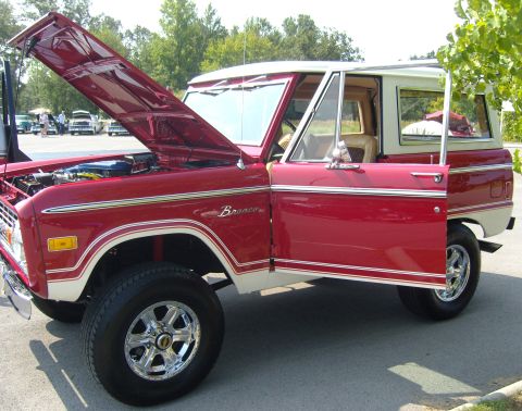 2007 Ford Mustang - A classic red Ford Bronco is parked with its hood and driver's door open, revealing its engine and interior.