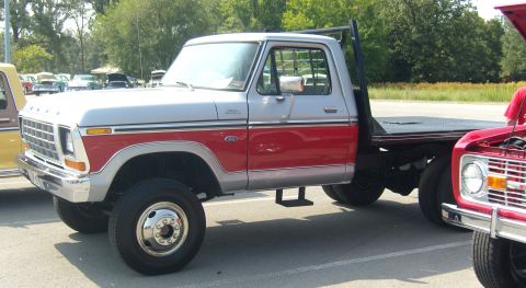 2007 Ford Mustang - A classic Ford F-Series truck with a flatbed is parked next to another vehicle.
