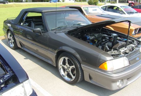 2007 Ford Mustang - Dark gray convertible Ford Mustang parked outdoors with hood open, other vehicles visible.