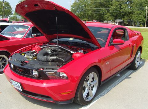 2007 Ford Mustang - Red 2007 Ford Mustang GT parked outdoors with its hood open, revealing the engine compartment.