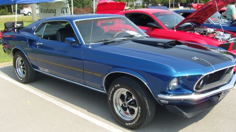 2007 Ford Mustang - A blue 1969 Ford Mustang Mach 1 is parked at a car show next to a red Ford Mustang.