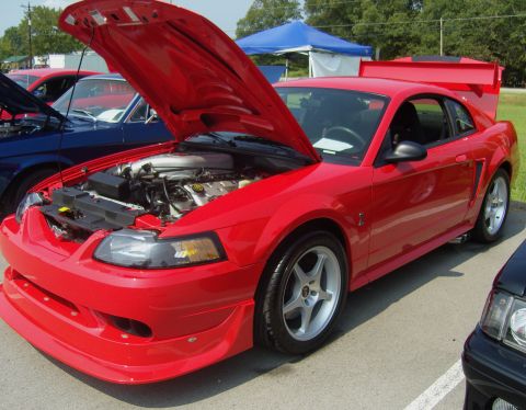 2007 Ford Mustang - A red Ford Mustang is displayed with its hood open, revealing the engine compartment and aftermarket modifications.