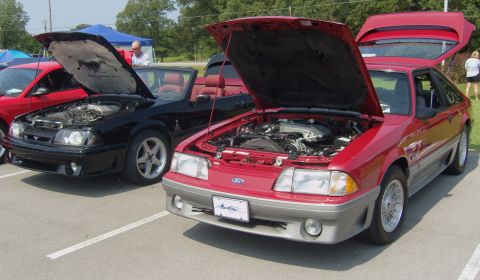 2007 Ford Mustang - A red 1987 Ford Mustang is displayed with its hood open, revealing the engine compartment. Another Mustang is visible to its left.