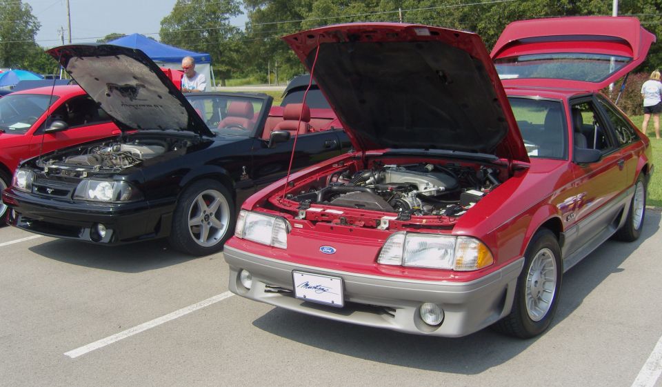 Red 1987 Ford Mustang with hood open, showing engine. License plate reads "Mustang"