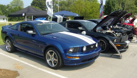 2007 Ford Mustang - Several Ford Mustangs are displayed at an outdoor event, with hoods open on some models.