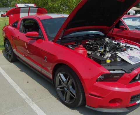 2007 Ford Mustang - A red 2007 Ford Mustang GT500 is displayed with its hood open, revealing the engine and a brochure on the fender.