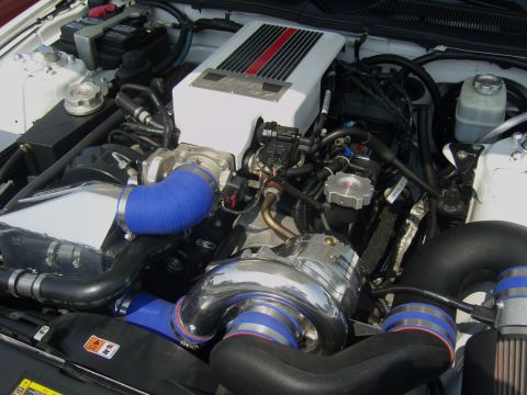 2007 Ford Mustang - The engine bay shows a white supercharger with red and black stripes, connected by blue and black hoses.