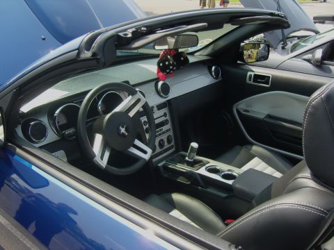 2007 Ford Mustang - The interior of a blue convertible Mustang shows its dashboard, steering wheel, and seats.