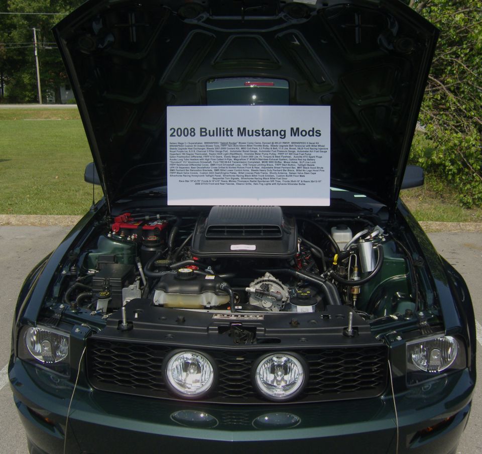Dark green 2008 Ford Mustang Bullitt with hood open, showing engine and a sign detailing modifications