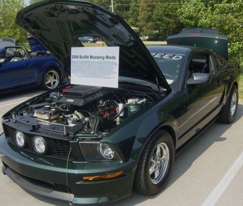 2007 Ford Mustang - A dark green 2008 Mustang is displayed with its hood and trunk open, revealing the engine and a sign listing modifications.