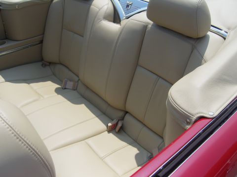 2007 Ford Mustang - The interior of a red convertible shows tan leather rear seats and seatbelts.