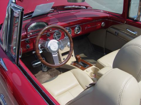 2007 Ford Mustang - The interior of a classic red 1955 Ford Fairlane convertible features tan leather seating and a distinctive wood-rimmed steering wheel.