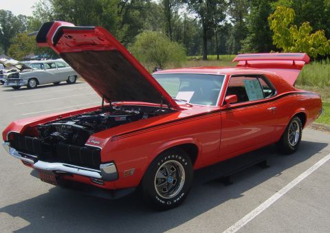 2007 Ford Mustang - Red classic car with hood open, parked at an outdoor event. Another car is visible in the background.