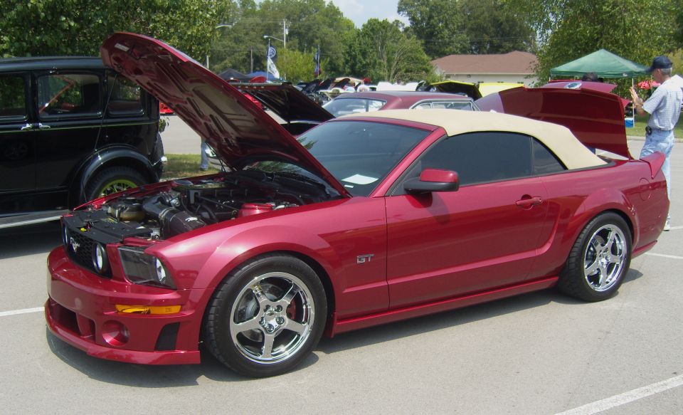 Red 2007 Ford Mustang GT convertible with hood and trunk open, parked next to a black vintage car