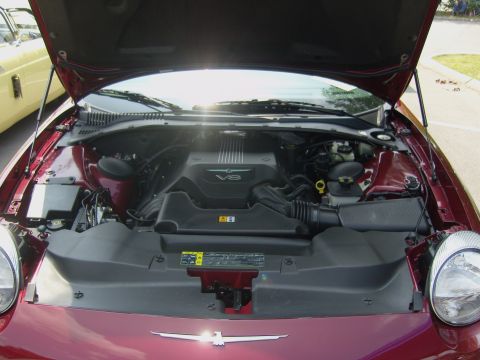 2007 Ford Mustang - The engine bay of a maroon 2002 Ford Thunderbird is visible, with a yellow car in the background.