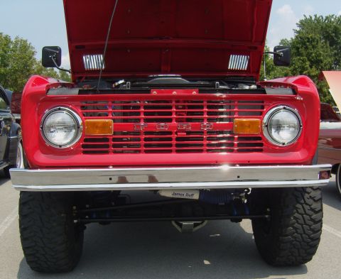 2007 Ford Mustang - Front view of a red Ford Bronco with its hood open, showing the grille and large off-road tires.