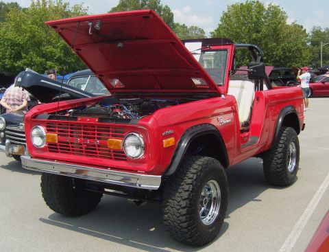 2007 Ford Mustang - A classic red Ford Bronco from 1975 is displayed with its hood open at a car show.