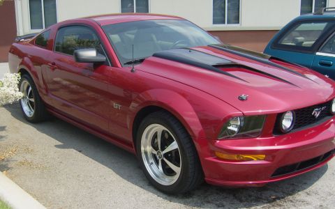 2007 Ford Mustang - A red Ford Mustang GT is parked in front of a building, with another vehicle visible to the right.