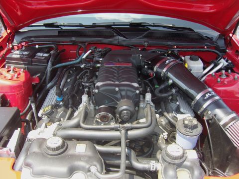 2007 Ford Mustang - Close-up view of a modified engine bay a prominent supercharger and custom intake system.