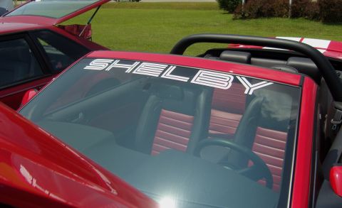 2007 Ford Mustang - A red 2007 Ford Mustang convertible with a Shelby banner is parked next to another red vehicle.