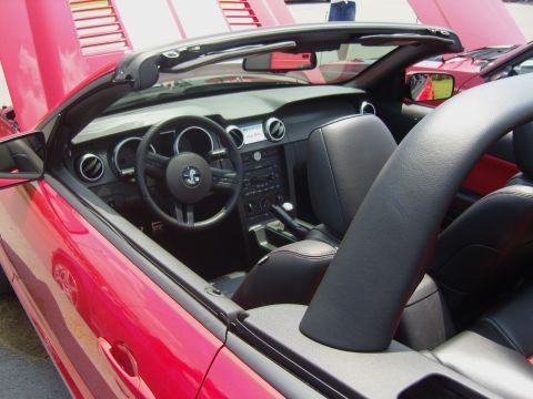 2007 Ford Mustang - Interior view of a red convertible, identified as a 2007 Ford Mustang, showing the dashboard and seats.