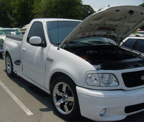 2007 Ford Mustang - A white Ford F-150 SVT Lightning pickup truck is shown with its hood up, revealing the engine compartment.