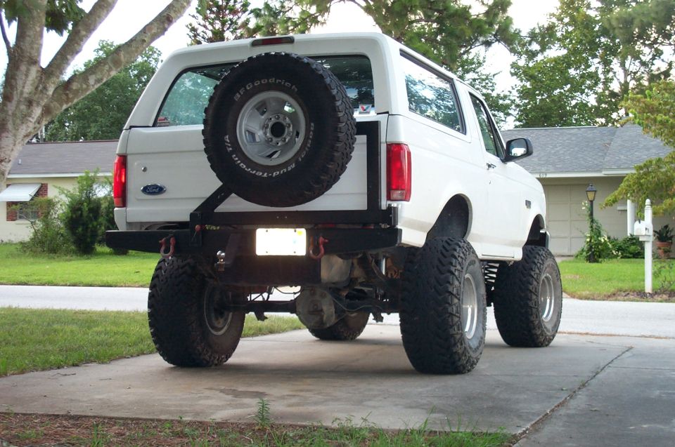 White lifted 1992-1996 Ford Bronco rear view with tire carrier in driveway