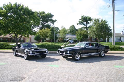 1968 Shelby GT500 - Two black 1968 Shelby GT500 Mustangs are parked side-by-side on a street.