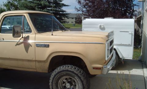 2006 Ford E350 - A tan Dodge D150 pickup truck from the late 1970s is parked next to a white trailer.