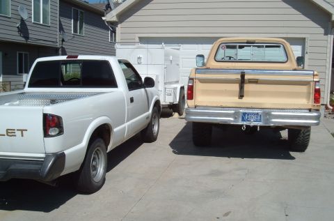 2006 Ford E350 - Two pickups parked tail-out on a residential concrete driveway: a white Chevrolet S-10 regular cab with a diamond-plate toolbox in the bed…