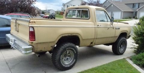 2006 Ford E350 - Rear three-quarter view of a tan 1970s Dodge Power Wagon short-bed 4x4 pickup parked at a suburban curb, showing faded paint, surface rust…