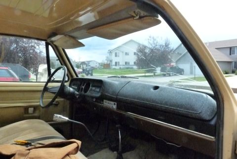 2006 Ford E350 - Interior of an older tan pickup or van looking across the cab from the driver's side: black padded dash with round gauge cluster and afterm…