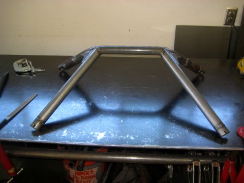 1996 Ford Bronco - A metal roll cage component rests on a workbench next to various tools.