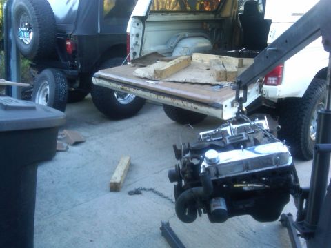 1986 Ford Bronco - An engine is being removed from a truck, with another vehicle visible in the background.