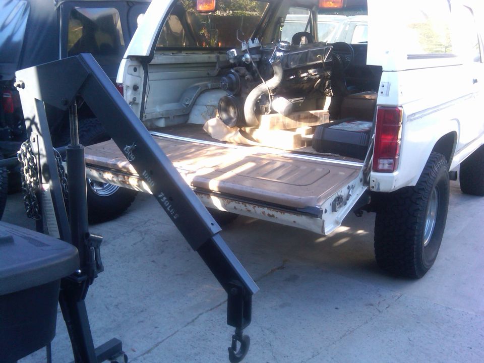 White 1986 Ford Bronco rear view with engine removed and hoist in bed. Text on hoist reads '1500 750LBS'
