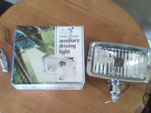 1988 Chevrolet Suburban - A box for a Sears driving light sits next to a chrome driving light on a wooden table.